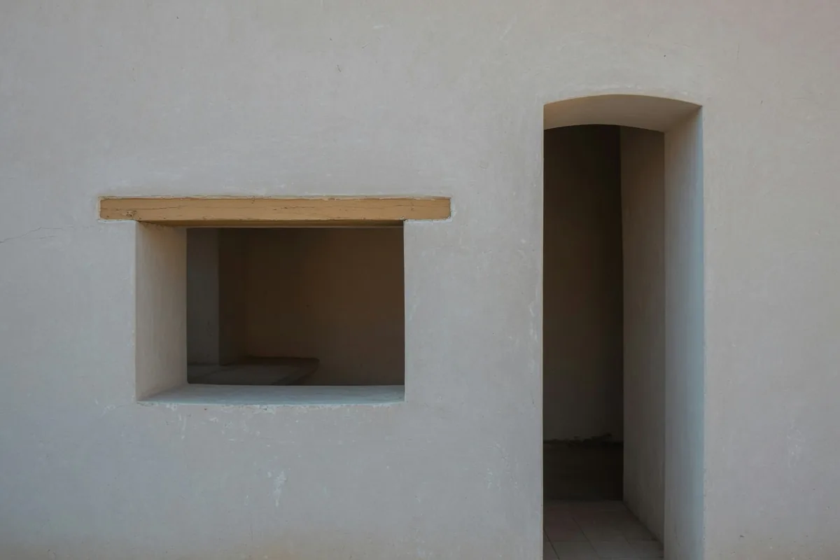 Deux mesures qui ne coïncident pas Dans un mur de plâtre, deux ouvertures côte à côte : l'une large et basse, l'autre haute et étroite.