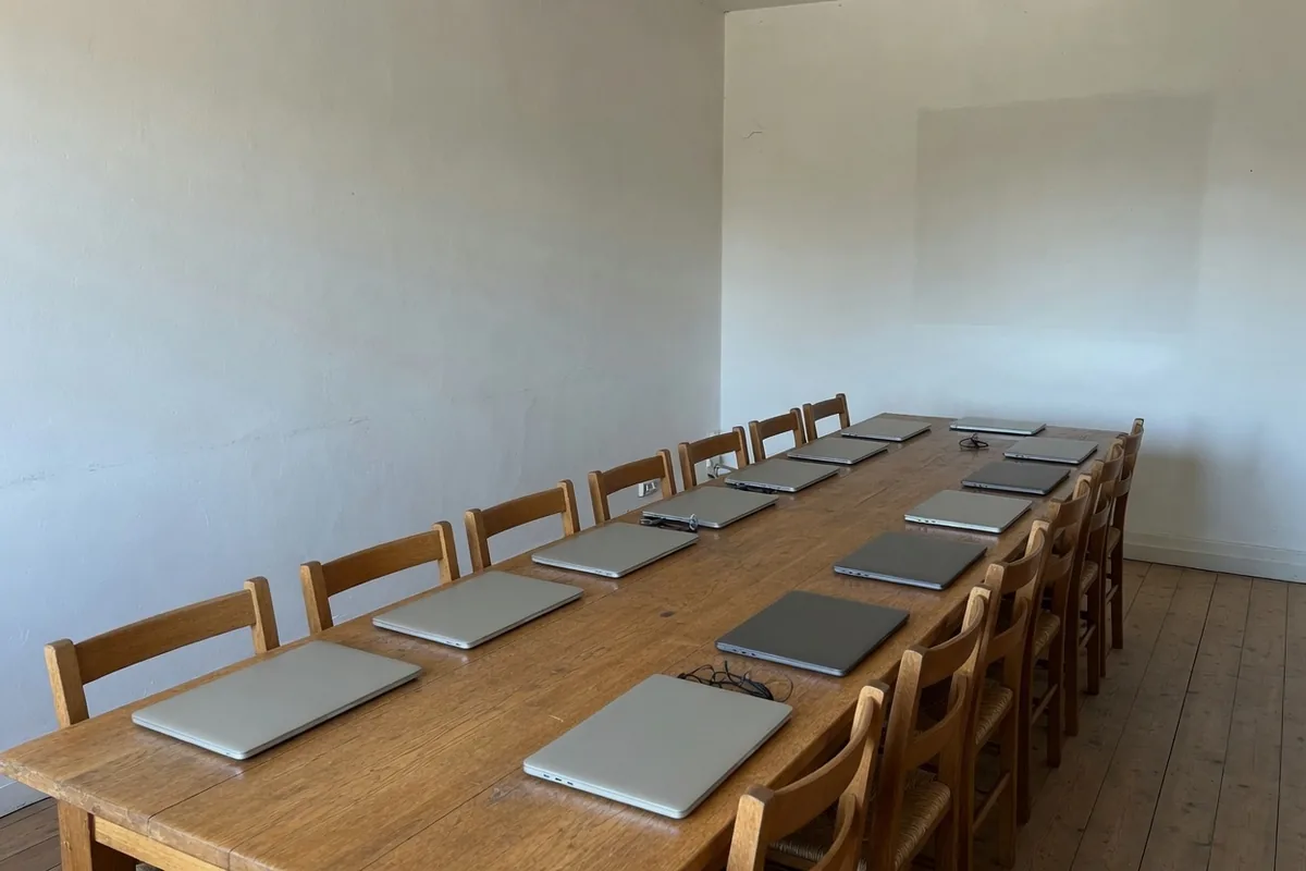 Une longue table de chêne, des chaises qui se font face, un ordinateur fermé devant chacune.