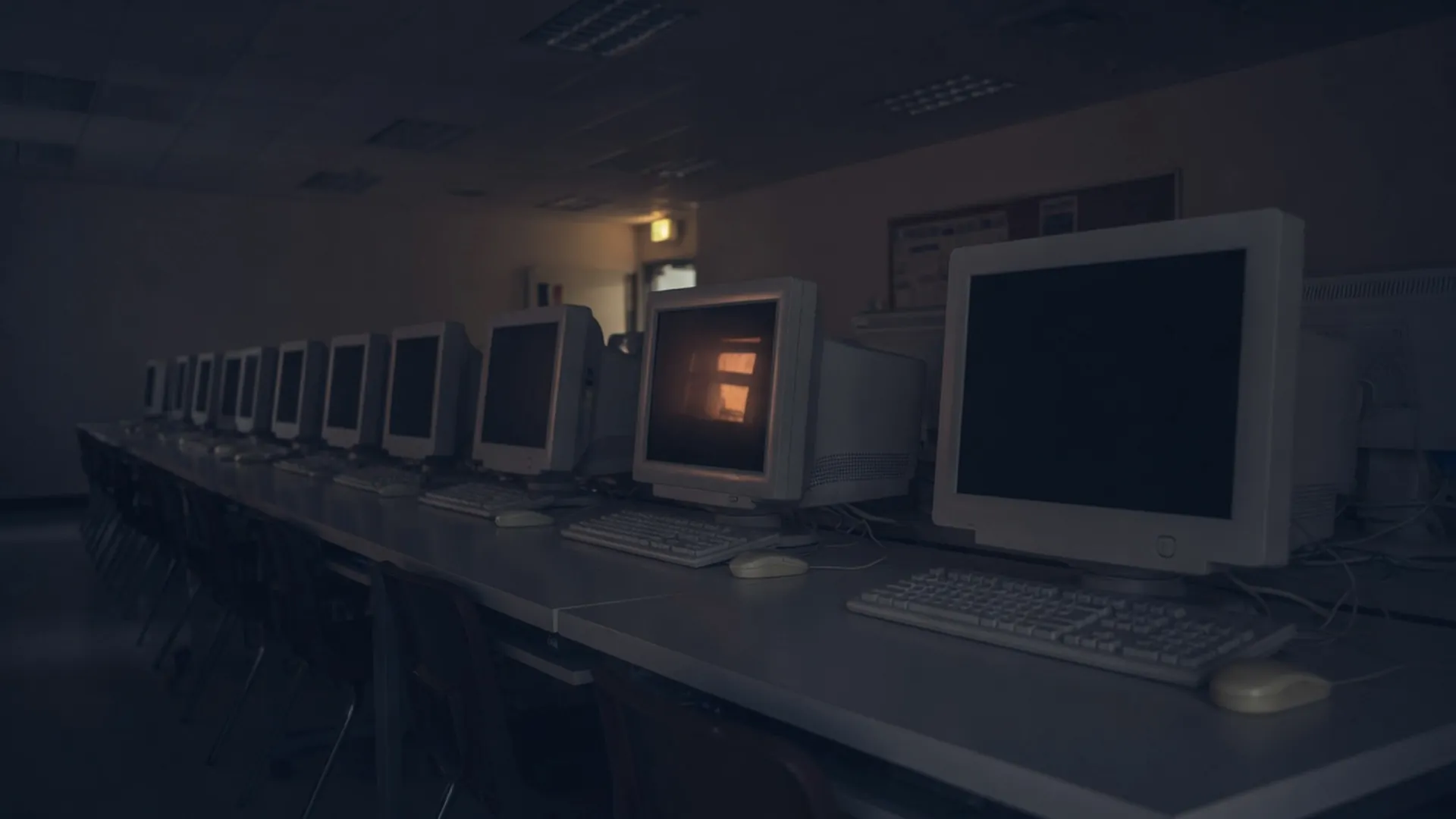 Salle informatique vide, dans la pénombre